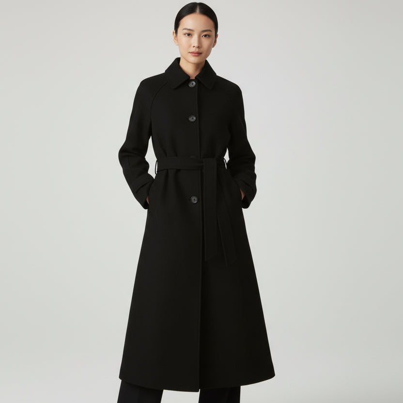 Woman wearing a black coat on a light gray background